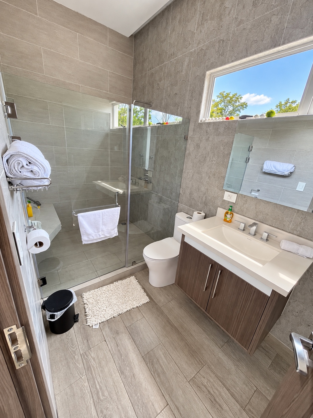 Baño con ducha de vidrio, lavabo y ventana
