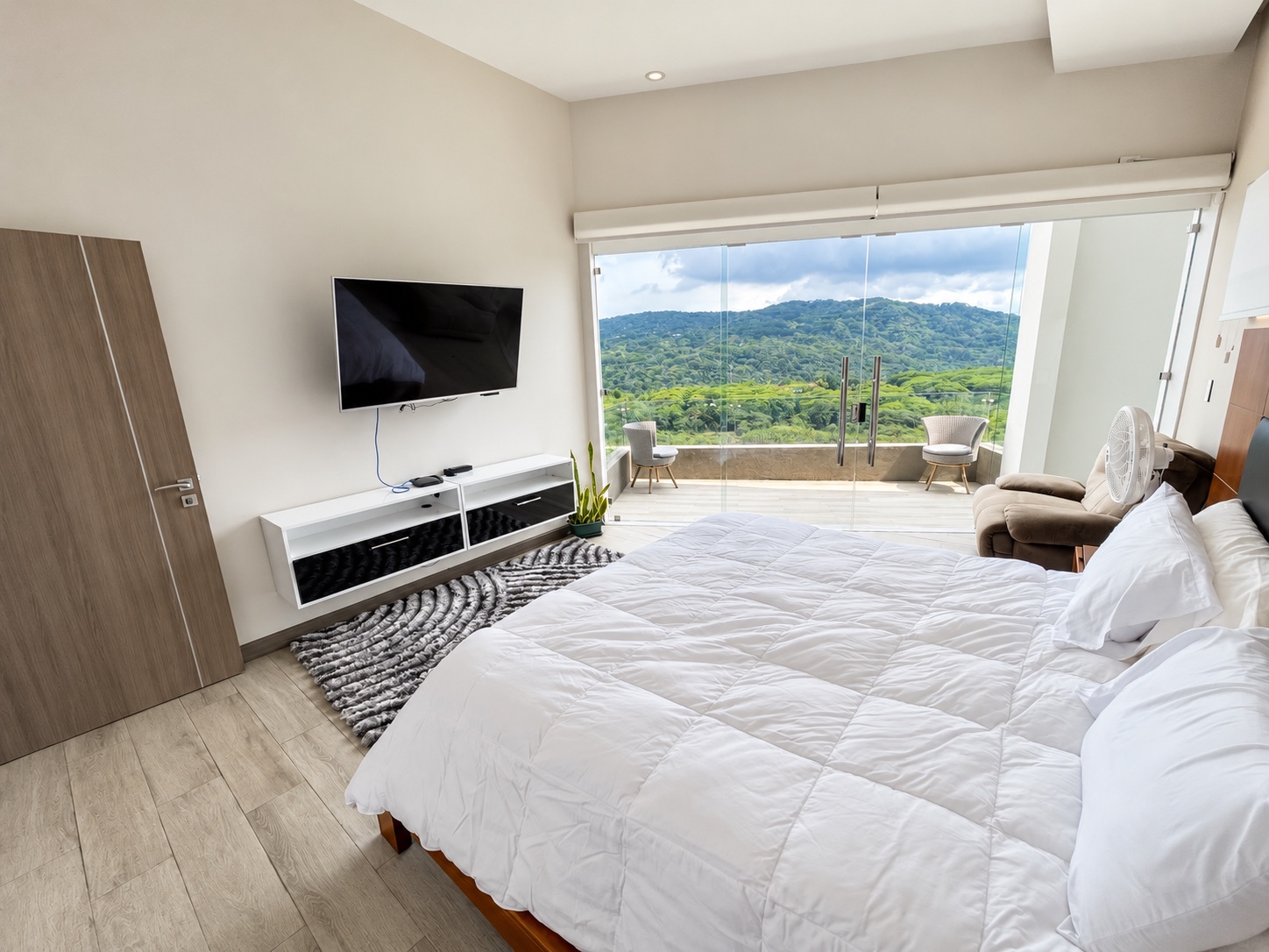 Cama, televisión y balcón con vista a las montañas